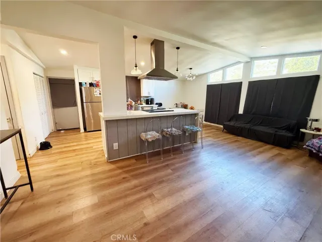 a large kitchen with stainless steel appliances a large counter top and wooden floors