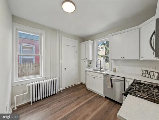 a kitchen with stainless steel appliances granite countertop a stove a sink and white cabinets