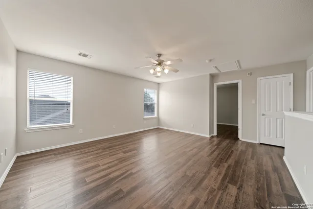a view of an empty room with wooden floor and a window