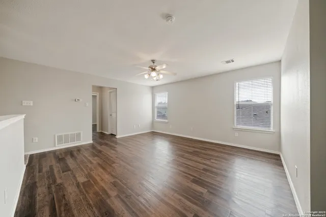 an empty room with wooden floor and windows