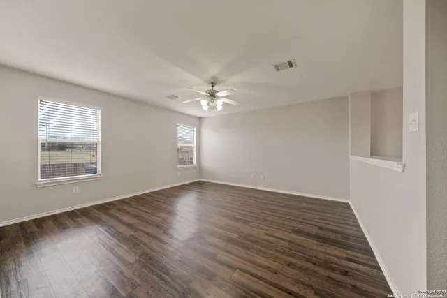 a view of an empty room with wooden floor and a window
