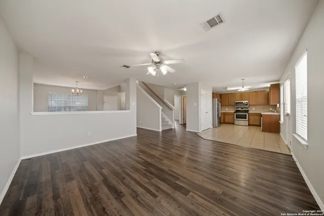 a view of a livingroom with furniture wooden floor a ceiling fan and windows