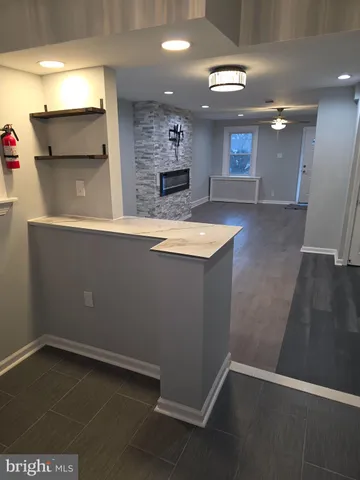 an empty room with wooden floor and kitchen view