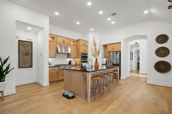 a view of a kitchen with kitchen island stainless steel appliances refrigerator stove dining table and chairs
