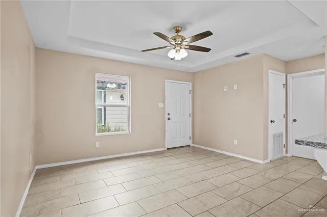 a view of an empty room with window and chandelier fan