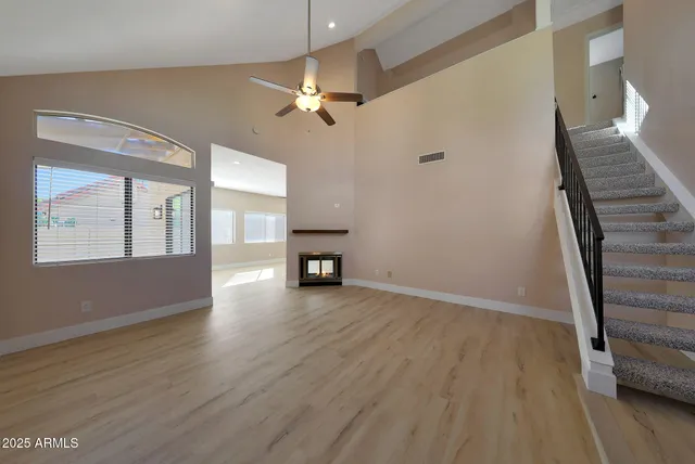 a view of an empty room with wooden floor and a ceiling fan