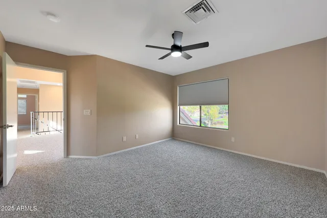 an empty room with chandelier fan and windows