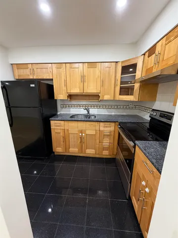 a kitchen with granite countertop a sink a stove and cabinets