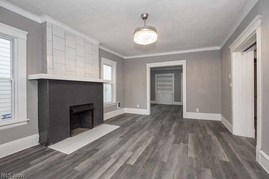 1892 Beersford Road Cleveland, OH 44112 - Photo 8 of 47 Unfurnished living room with a fireplace, a textured ceiling, dark hardwood / wood-style flooring, and ornamental molding