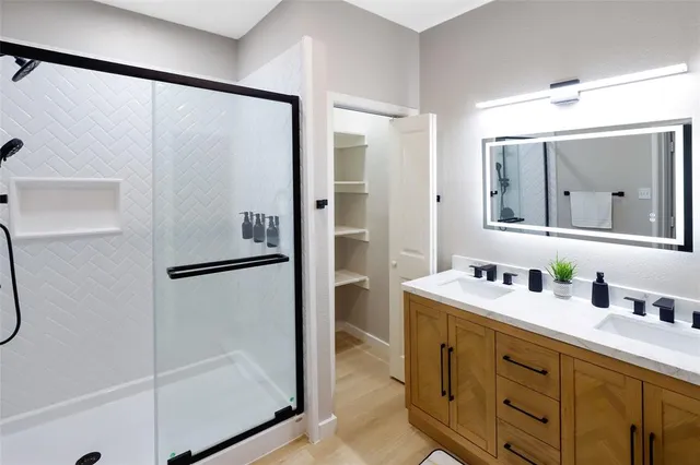 a bathroom with a double vanity sink mirror and shower