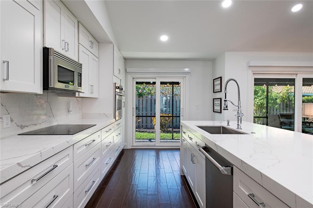 748 Reef Point Circle Naples, FL 34108 - Photo 9 of 23 Kitchen featuring light stone countertops, recessed lighting, white cabinetry, dark wood-style floors, and stainless steel appliances