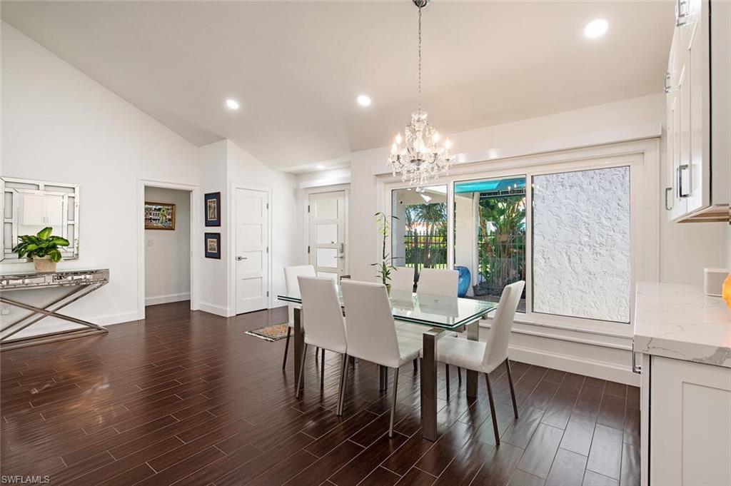 748 Reef Point Circle Naples, FL 34108 - Photo 11 of 23 Dining space with dark wood-type flooring, recessed lighting, a chandelier, and vaulted ceiling