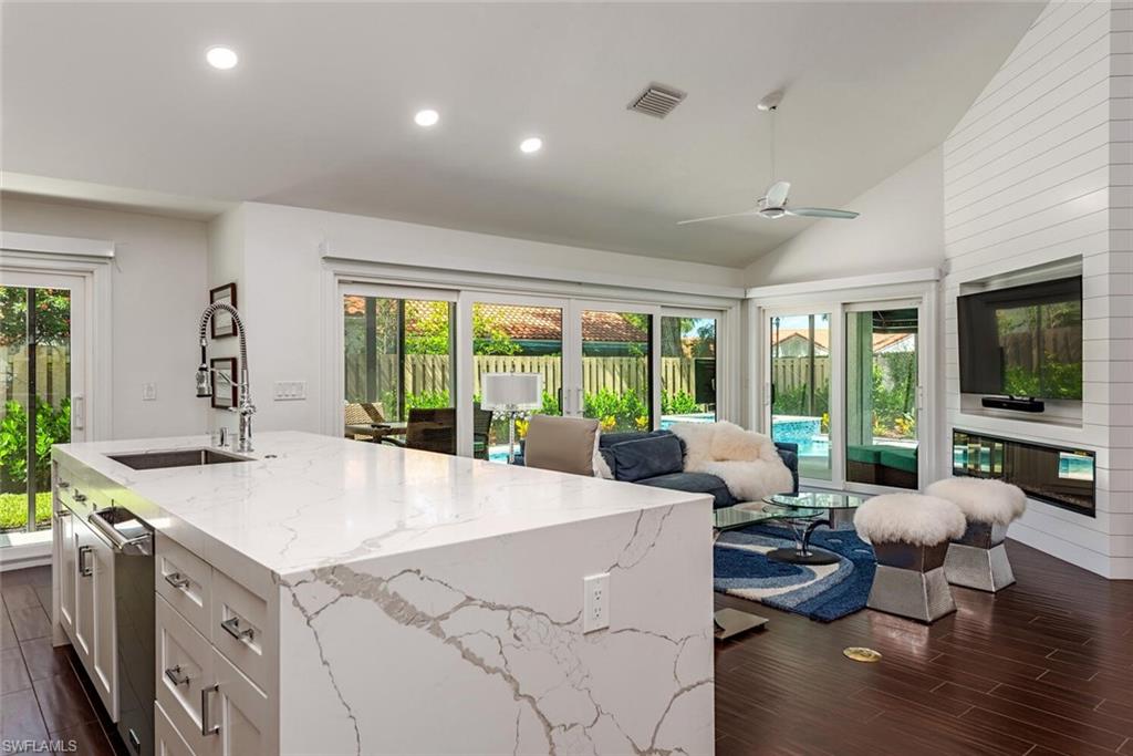748 Reef Point Circle Naples, FL 34108 - Photo 12 of 23 Kitchen featuring recessed lighting, wood finish floors, white cabinets, plenty of natural light, and light stone counters
