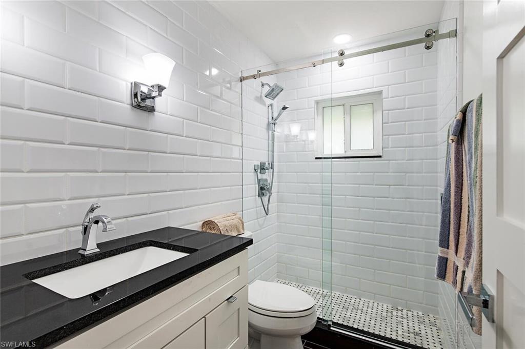 748 Reef Point Circle Naples, FL 34108 - Photo 16 of 23 Full bath featuring a stall shower, vanity, tile walls, and backsplash