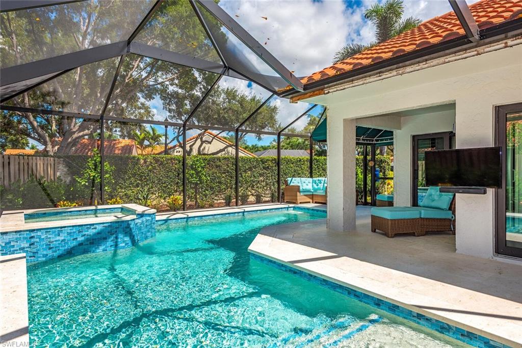 748 Reef Point Circle Naples, FL 34108 - Photo 18 of 23 View of swimming pool featuring a patio area, glass enclosure, a sunroom, and a pool with connected hot tub