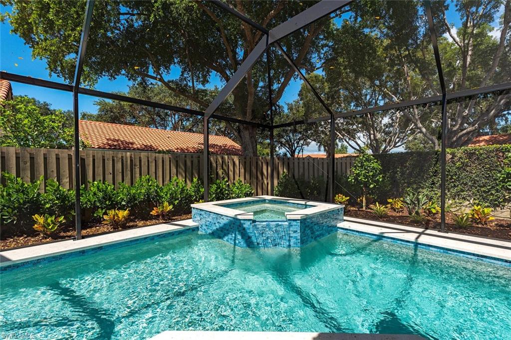 748 Reef Point Circle Naples, FL 34108 - Photo 21 of 23 View of pool featuring glass enclosure, a sunroom, a pool with connected hot tub, and a fenced backyard