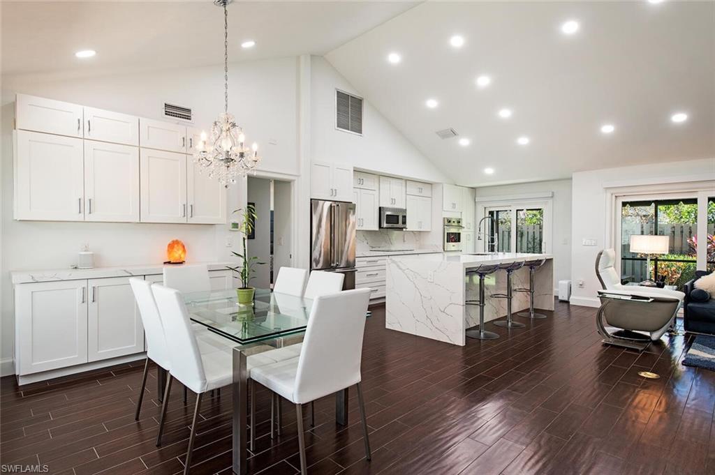 748 Reef Point Circle Naples, FL 34108 - Photo 6 of 23 Dining room featuring wood tiled floors, high vaulted ceiling, recessed lighting, and a chandelier