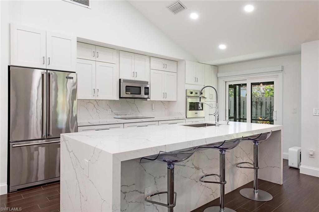 748 Reef Point Circle Naples, FL 34108 - Photo 8 of 23 Kitchen featuring wood tiled floors, appliances with stainless steel finishes, light stone counters, recessed lighting, and white cabinetry
