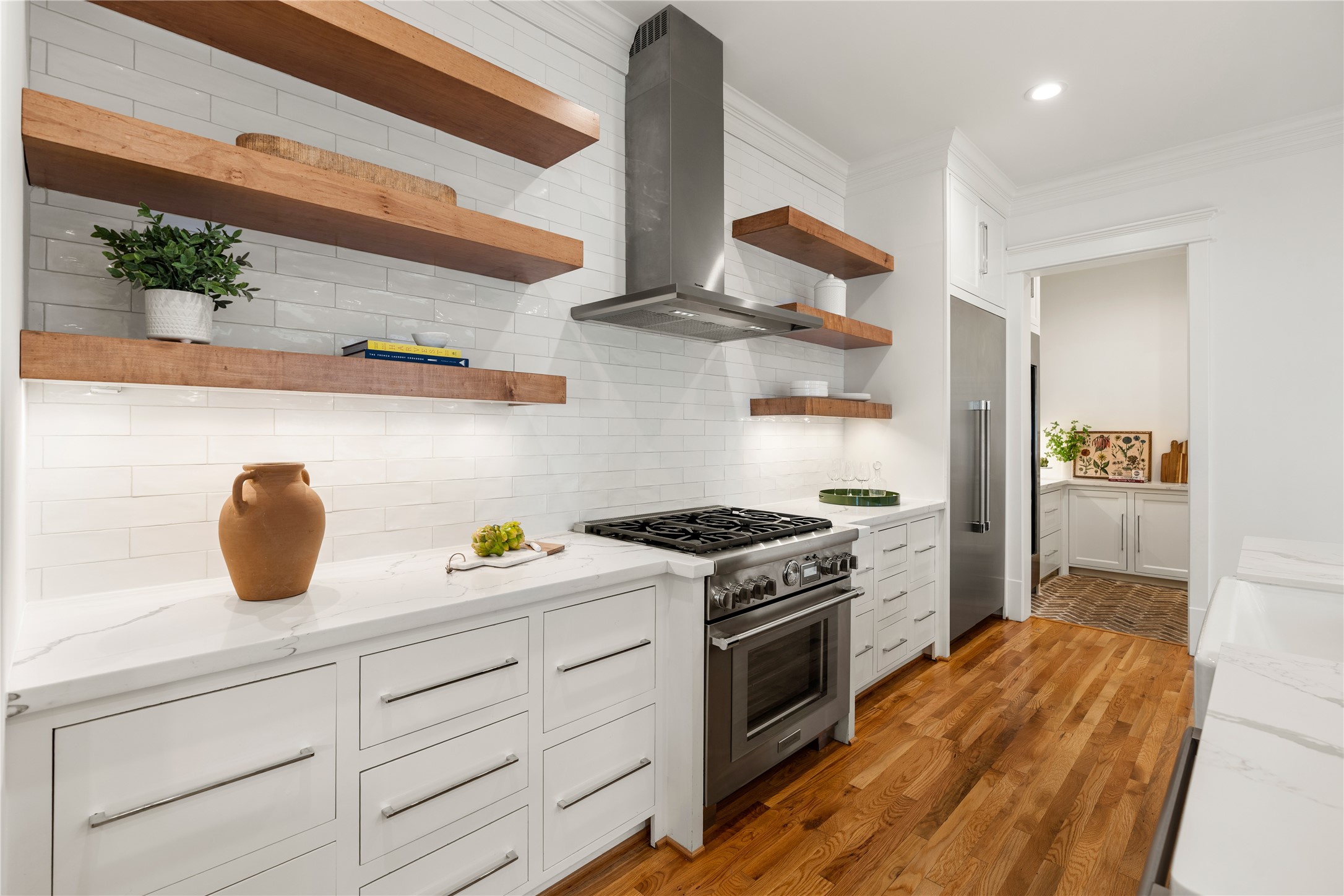 925 Tulane Street, Unit A Houston, TX 77008 - Photo 18 of 49 The beautifully executed kitchen includes a subway tile backsplash that extends to the ceiling and custom-made white oak floating shelves with integrated lighting.