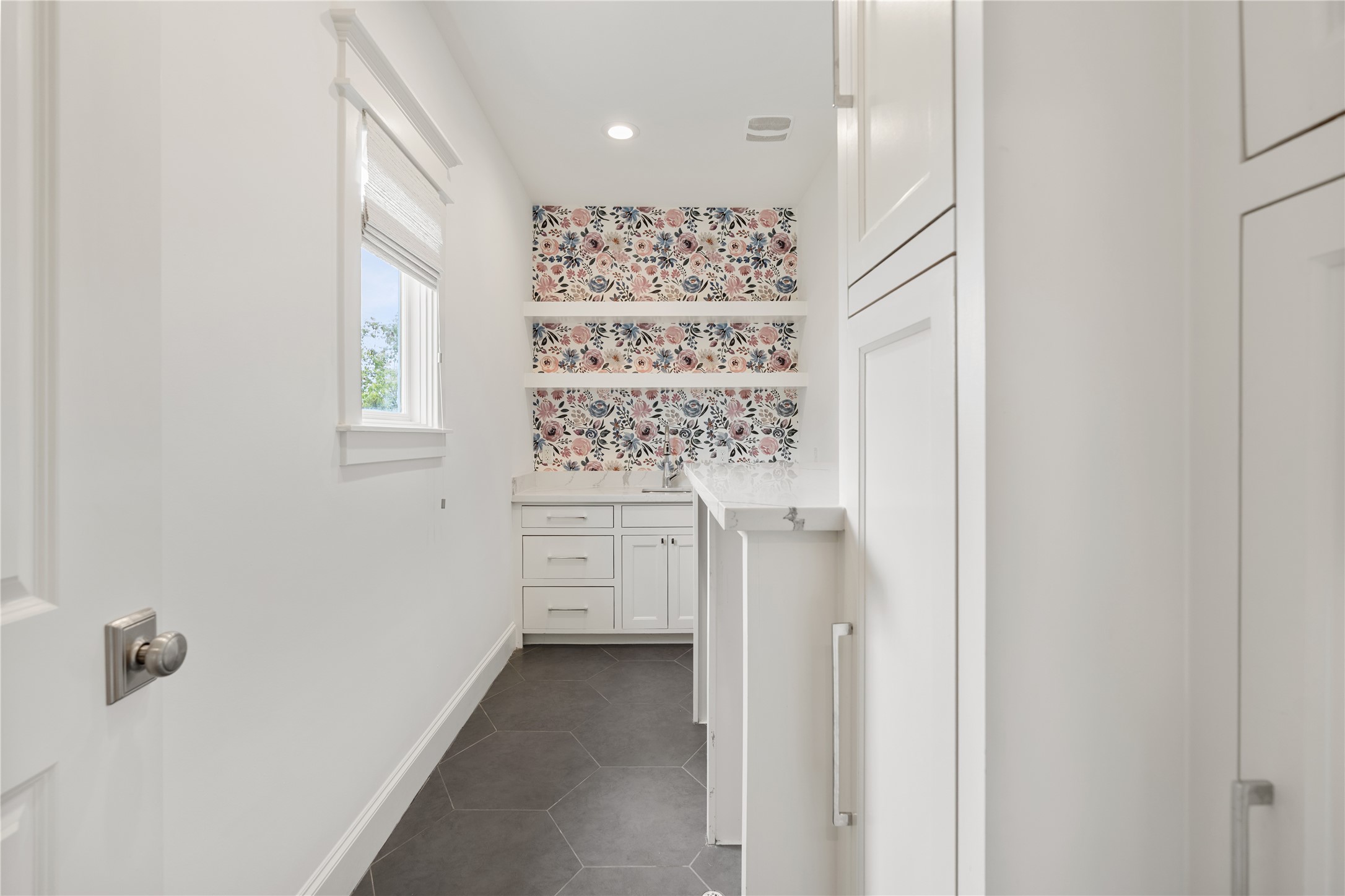 925 Tulane Street, Unit A Houston, TX 77008 - Photo 32 of 49 Laundry day is a joy in this delightful, windowed utility room featuring floral wallpaper, soft-close cabinetry, marble countertops, a sink and a washer-dryer enclosure.