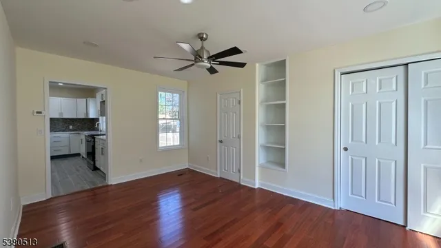 a view of empty room with wooden floor and kitchen view