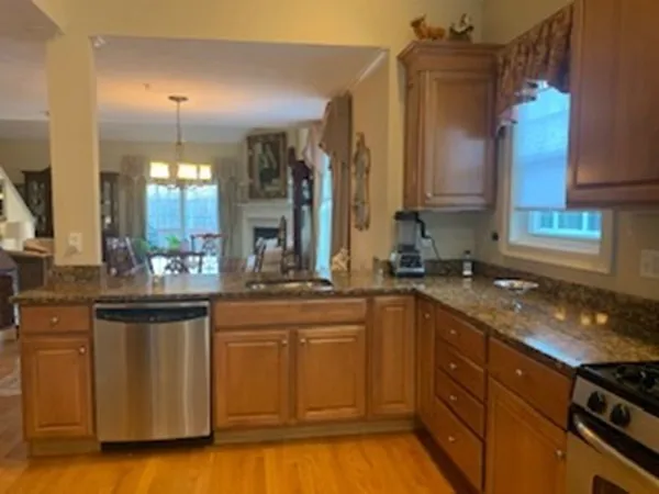 a kitchen with stainless steel appliances granite countertop a sink a stove and a wooden cabinets