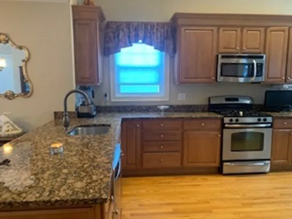 a kitchen with stainless steel appliances granite countertop a stove a sink and a microwave