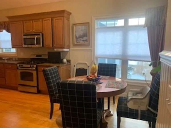 a kitchen with stainless steel appliances a stove a sink a microwave a dining table and chairs