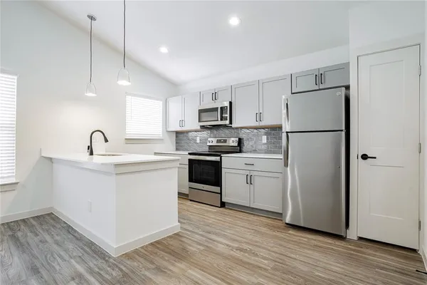 a kitchen with a refrigerator white cabinets and wooden floor