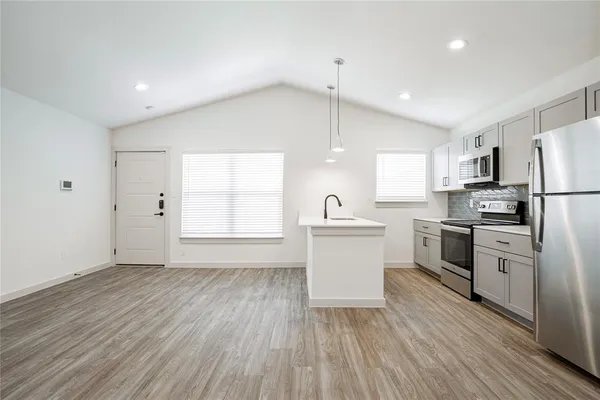 a large kitchen with white cabinets stainless steel appliances a sink and a center island