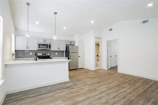 a large white kitchen with stainless steel appliances granite countertop a stove a sink and white cabinets