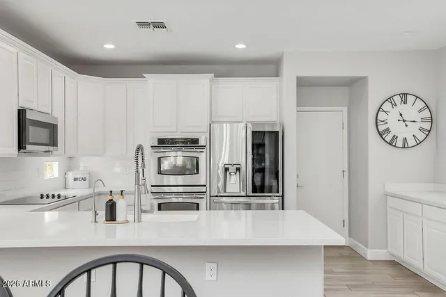 a kitchen with stainless steel appliances granite countertop a refrigerator a stove a sink and a microwave with wooden floor