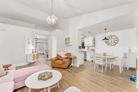a dining room with wooden floor a chandelier a wooden table and chairs