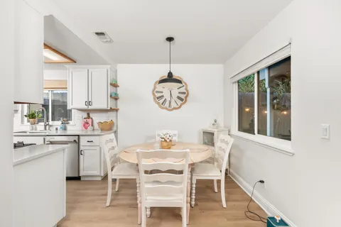 a dining room with wooden floor a chandelier a wooden table and chairs