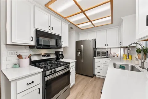 a kitchen with cabinets stainless steel appliances and wooden floor