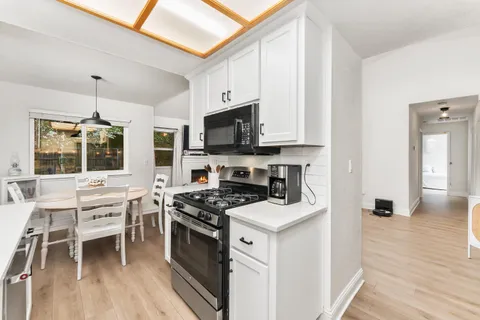 a kitchen with stainless steel appliances a stove a sink and white cabinets