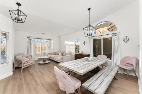a living room with dining table and a chandelier