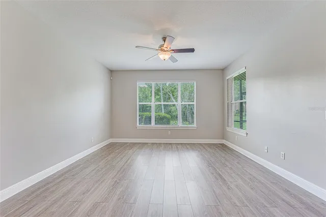 a view of empty room with wooden floor and kitchen