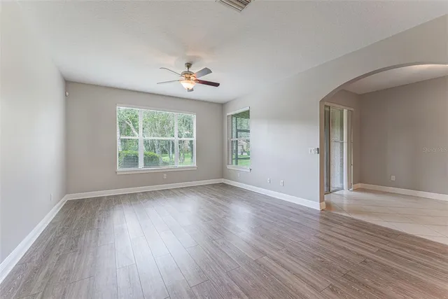 a view of a big room with wooden floor a chandelier fan and windows
