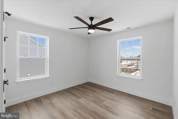 a view of an empty room with a window and wooden floor