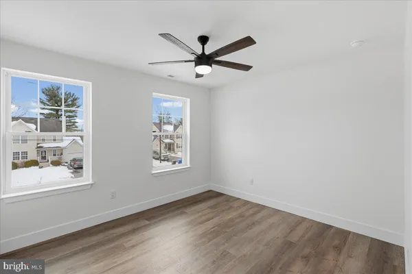 an empty room with wooden floor fan and windows