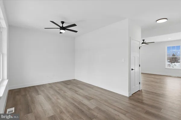 an empty room with wooden floor closet and windows