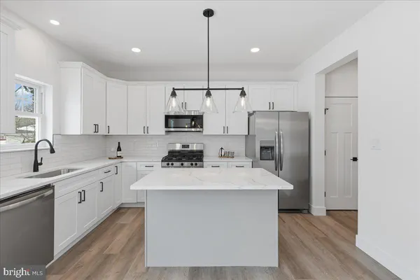 a kitchen with stainless steel appliances a sink a stove a refrigerator a center island and cabinets