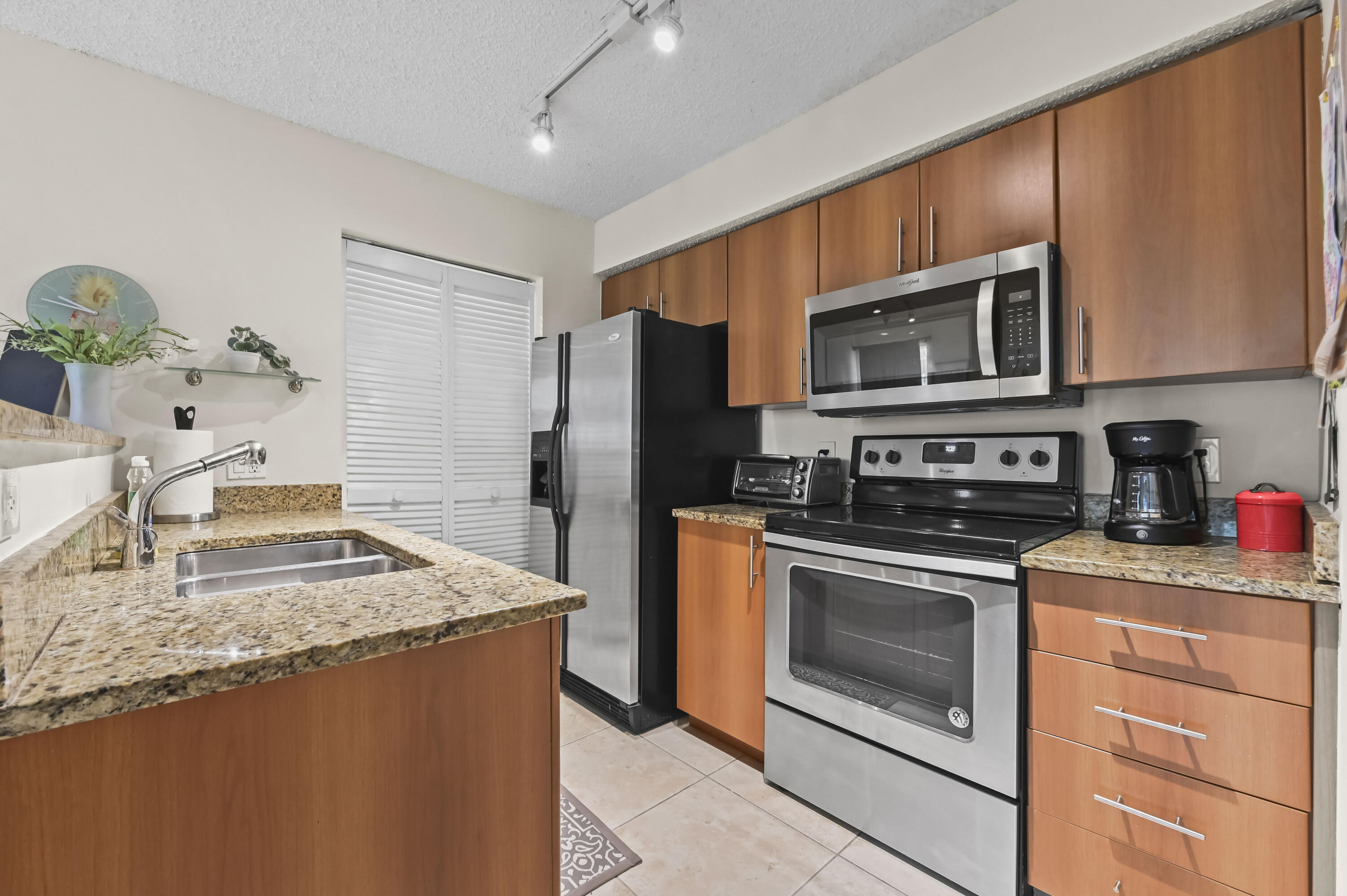 1205 Crystal Way, Unit K Delray Beach, FL 33444 - Photo 9 of 25 a kitchen with stainless steel appliances granite countertop a stove microwave and refrigerator