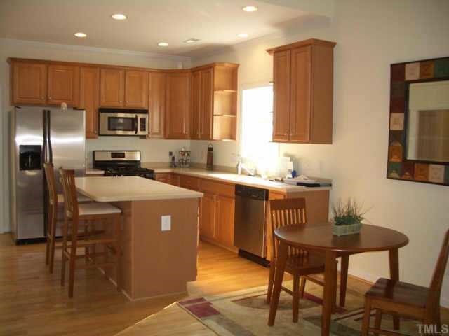 7306 Caversham Way Raleigh, NC 27617 - Photo 4 of 6 a kitchen with a refrigerator a stove a sink a dining table and chairs