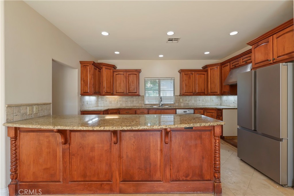 17100 Apple Street Bellflower, CA 90706 - Photo 11 of 38 a kitchen with kitchen island granite countertop wooden cabinets a refrigerator and a sink