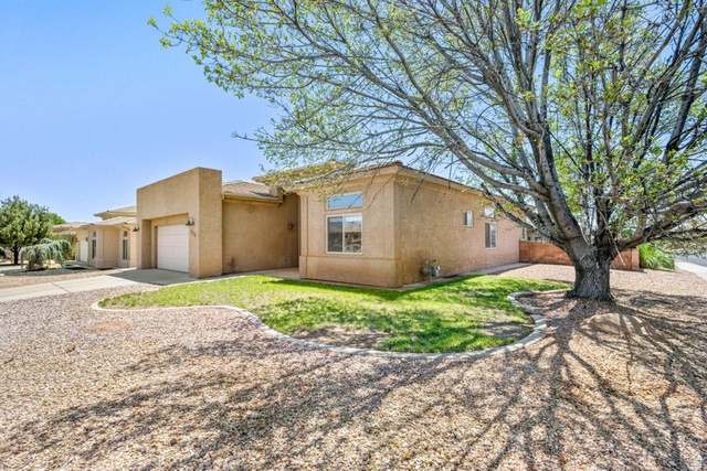 2226 East 140 South St. George, UT 84790 - Photo 2 of 20 Stucco exterior residence featuring a front-facing garage, a gravel driveway, and mature landscaping with a prominent tree