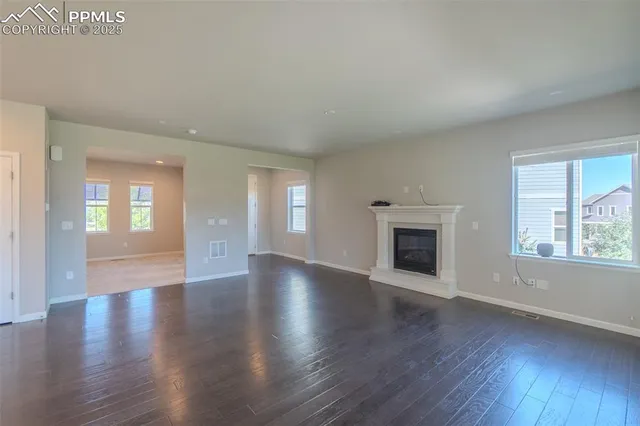 an empty room with wooden floor fireplace and windows