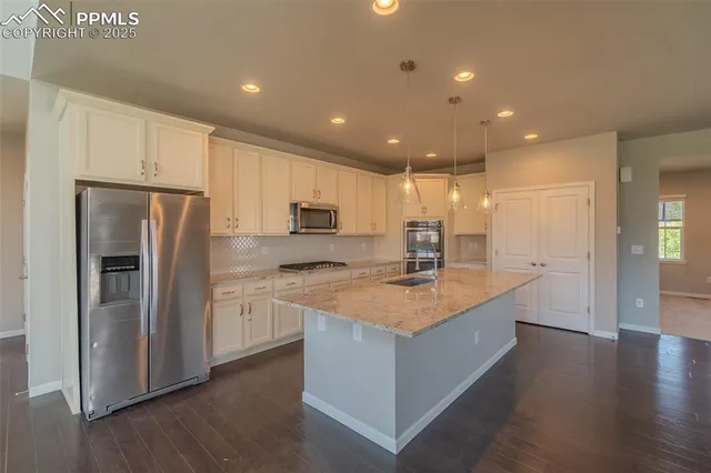 a kitchen with stainless steel appliances granite countertop a refrigerator a sink dishwasher a stove and a refrigerator with wooden floor