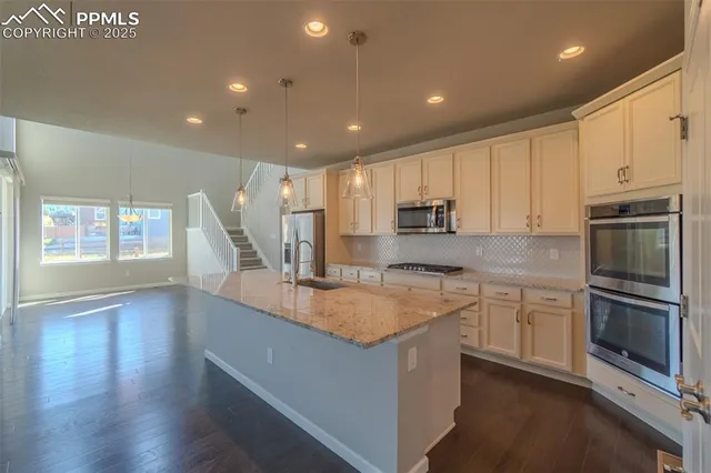 a large kitchen with stainless steel appliances granite countertop a large counter top a stove and a sink